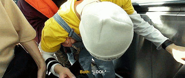 a person wearing a white hat and a yellow shirt is being pushed down an escalator by another person .