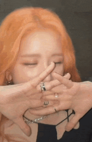 a woman with red hair is making a funny face with her hands .