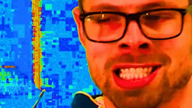 a close up of a man wearing glasses and a beard smiling .