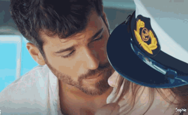 a man wearing a captain 's hat is kissing a woman on the cheek