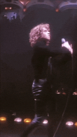 a man in a black shirt is dancing on a stage in a dark room