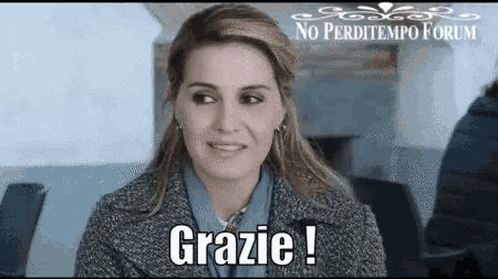 a woman in a grey coat is smiling and says grazie !