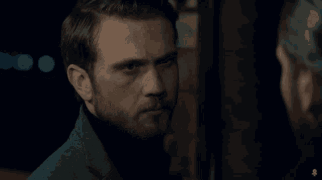 a man with a beard looks at another man with a skull on his head