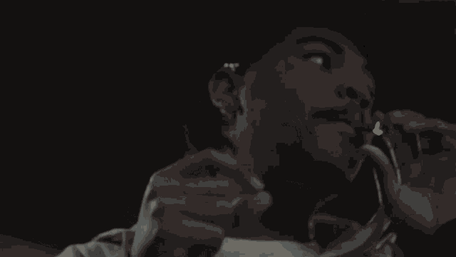 a man is smoking a cigarette with smoke coming out of his mouth in a dark room .