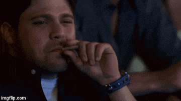 a man is smoking a cigarette while a woman looks on .