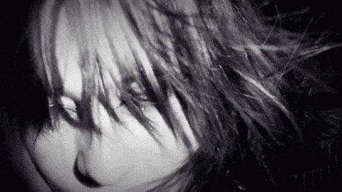 a close up of a woman 's face with long hair in a black and white photo .