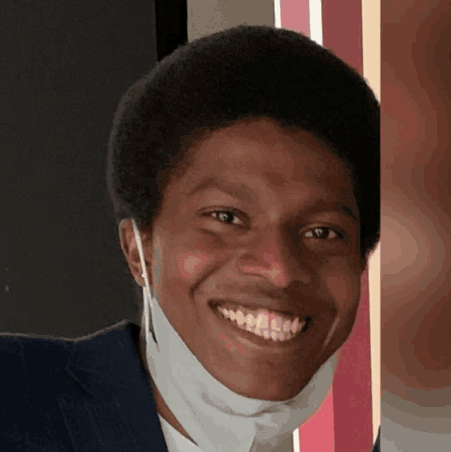 a man wearing a face mask is smiling and looking at the camera
