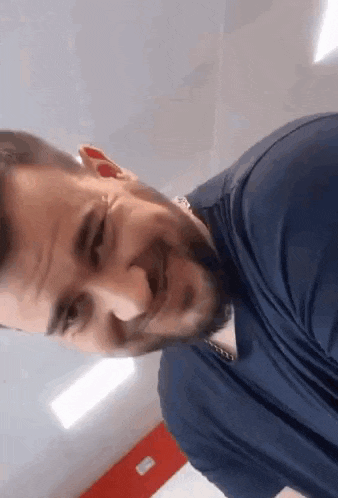 a man with a beard wearing a blue shirt is smiling .
