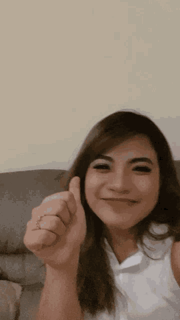 a woman is smiling and giving a thumbs up sign