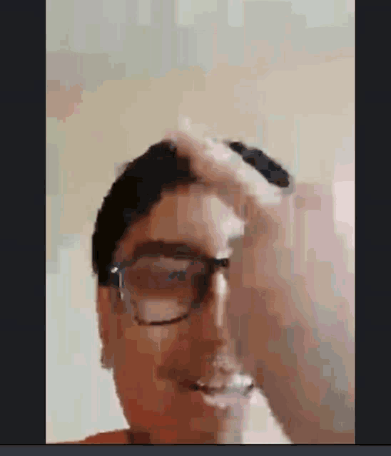a man wearing glasses holds his hand to his head