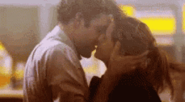 a man and a woman are kissing each other in a restaurant .