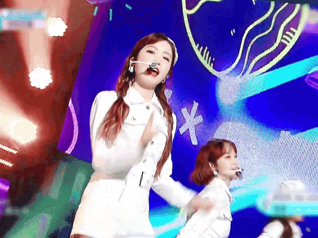 a woman in a white dress is dancing on a stage with a heart in the background