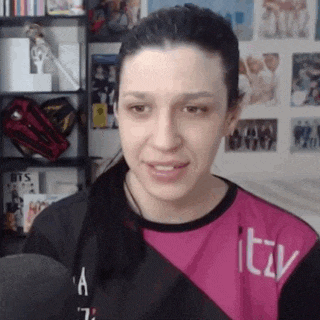 a woman wearing a pink and black shirt with the word itv on it is talking into a microphone .
