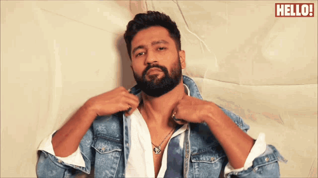 a man with a beard is wearing a denim jacket and a white shirt with the words hello on the bottom right