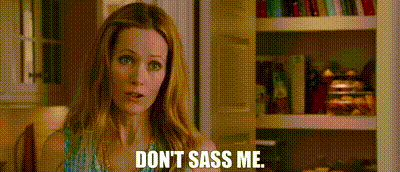 a woman is sitting in front of a bookshelf and says `` don t sass me '' .