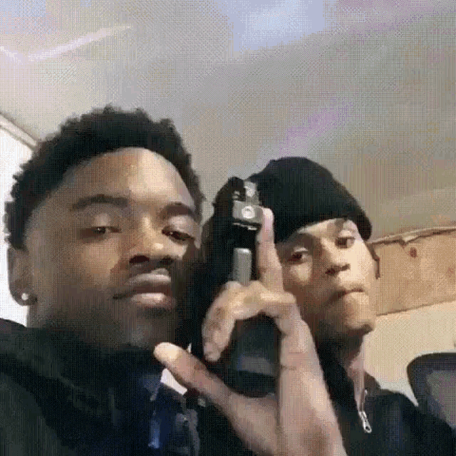 two men are taking a selfie with a gun .
