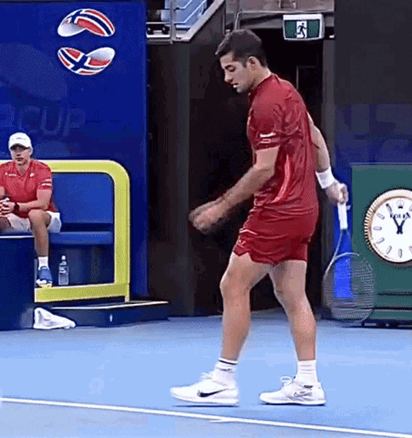a man in a red shirt is holding a tennis racquet on a blue court