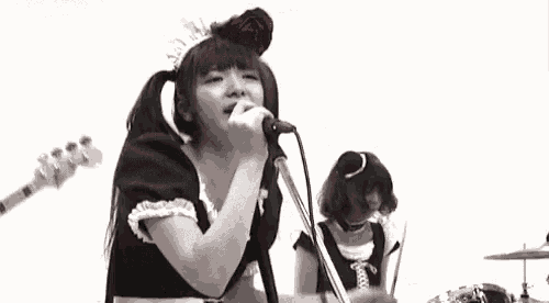 a maid is singing into a microphone in a band .