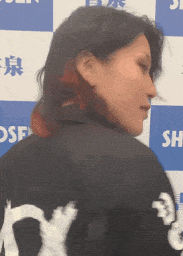 a woman stands in front of a blue and white backdrop with the word sh on it
