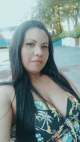 a woman with long black hair is wearing a floral dress and looking at the camera