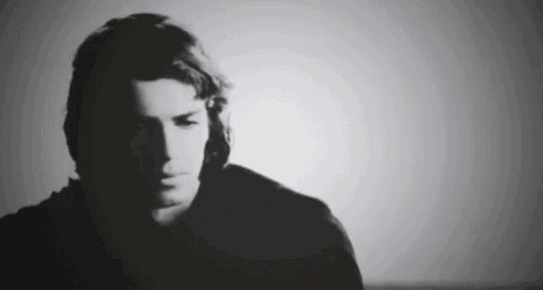 a black and white photo of a man 's face in a dark room .