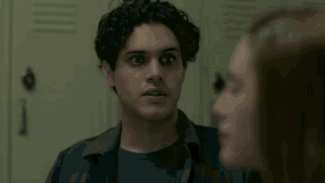 a man with curly hair is looking at a woman in a locker room