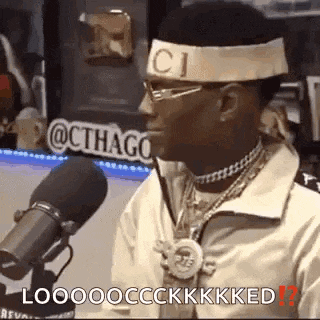 a man wearing a gucci headband and glasses is talking into a microphone .