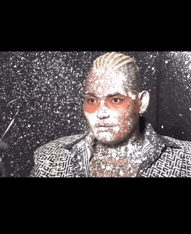 a man with white powder on his face is wearing a black and white jacket .