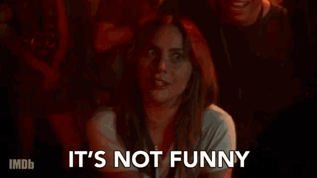 a woman is sitting in a crowd watching a movie and says `` it 's not funny '' .