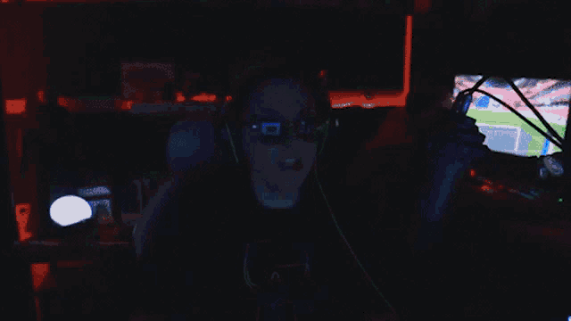 a person wearing headphones and sunglasses is sitting in front of a microphone in a dark room
