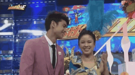 a man in a pink suit and tie is standing next to a woman