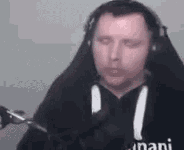a man wearing headphones and a black sweatshirt is sitting in front of a microphone .