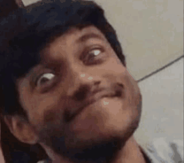 a man with a beard is making a funny face while looking up .