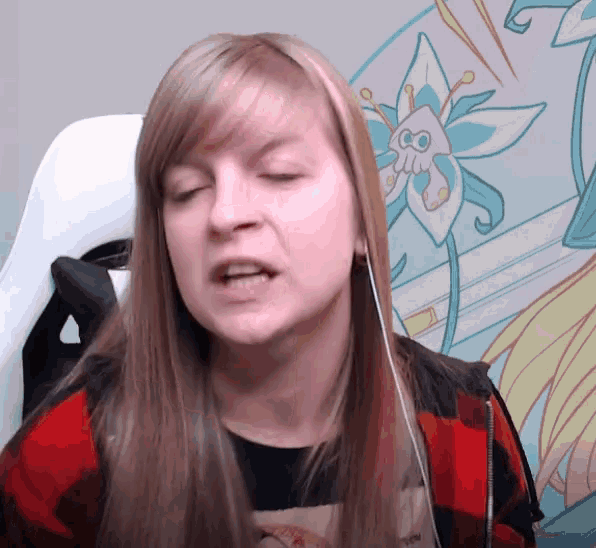 a woman wearing a plaid shirt and headphones is making a funny face