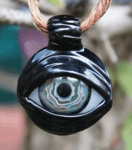 a close up of a necklace with a black eye on it