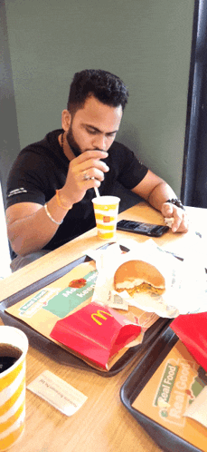 a man sits at a mcdonald 's table drinking a drink