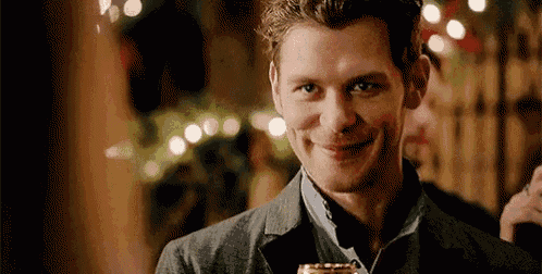 a man in a suit is smiling and holding a glass .