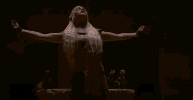 a woman with her arms outstretched is holding a fireball .