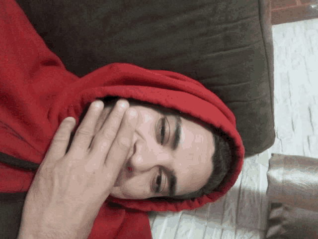a man wearing a red hoodie covering his mouth