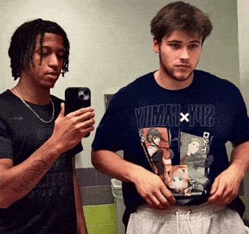 a man wearing a shirt that says yuma x yu2 is taking a picture of himself