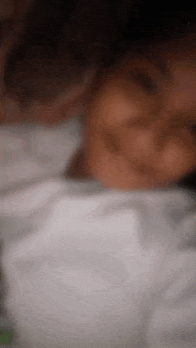 a blurry picture of a person laying on a bed with a white blanket