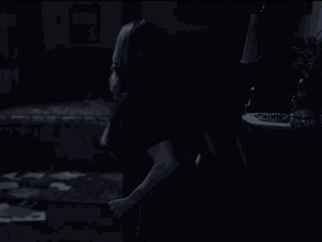a woman in a dark room with a lamp