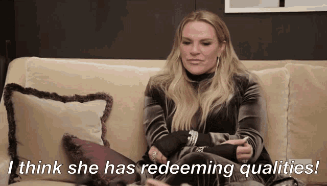 a woman sitting on a couch with the words i think she has redeeming qualities