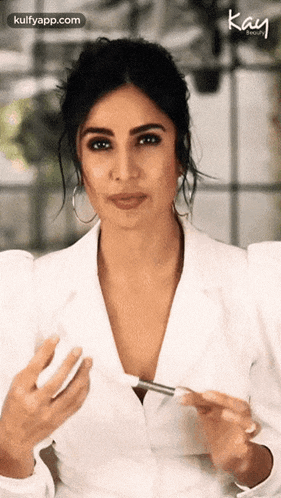 a woman in a white jacket is holding a makeup brush