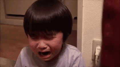 a little boy is crying in a room with his eyes closed .