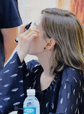 a woman sitting at a table with a bottle of aquafina water nearby