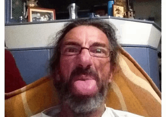 a man with glasses and a beard sticking out his tongue