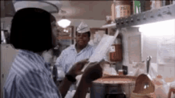 a woman in a striped shirt is standing in a kitchen talking on a cell phone