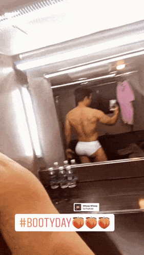 a man taking a picture of himself in a bathroom mirror with #bootyday written on the bottom