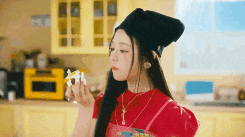a woman in a red dress and a black hat is blowing bubbles in the kitchen .